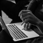 grayscale photo of person using MacBook